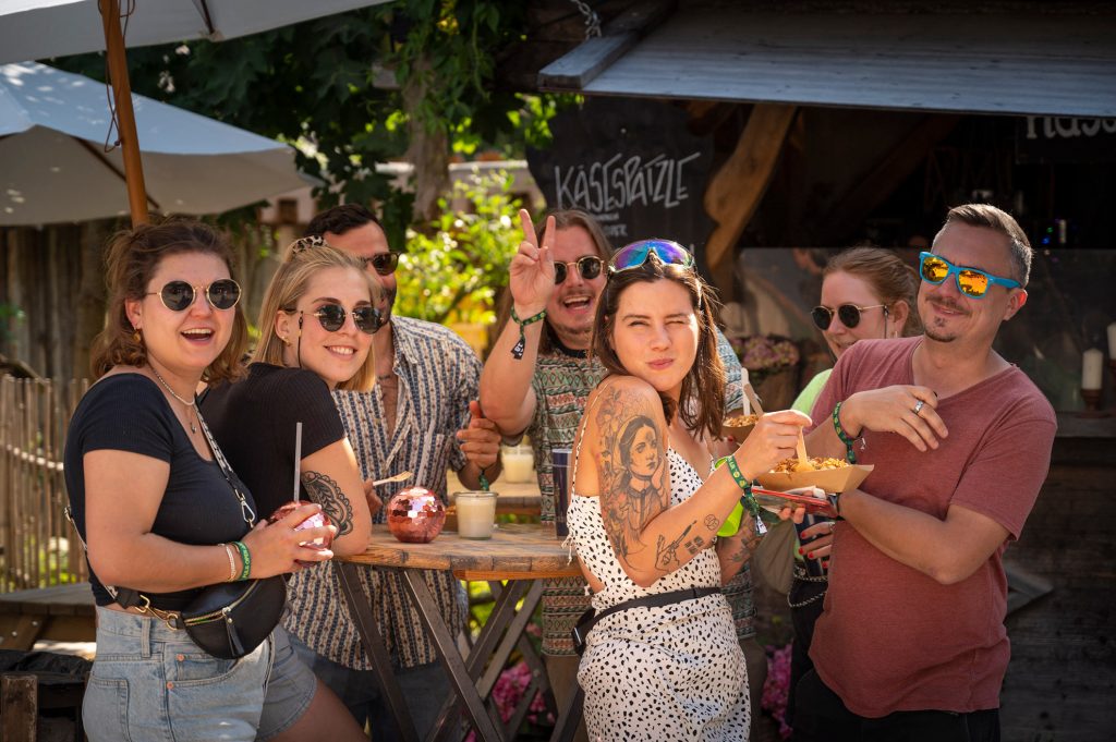 Bild von Gästen des PULS OPEN AIR die auf dem Festivalgelände etwas essen und trinken.