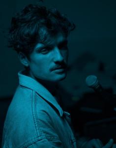 PaulWetz mit Mikrofon in blaues Licht getaucht